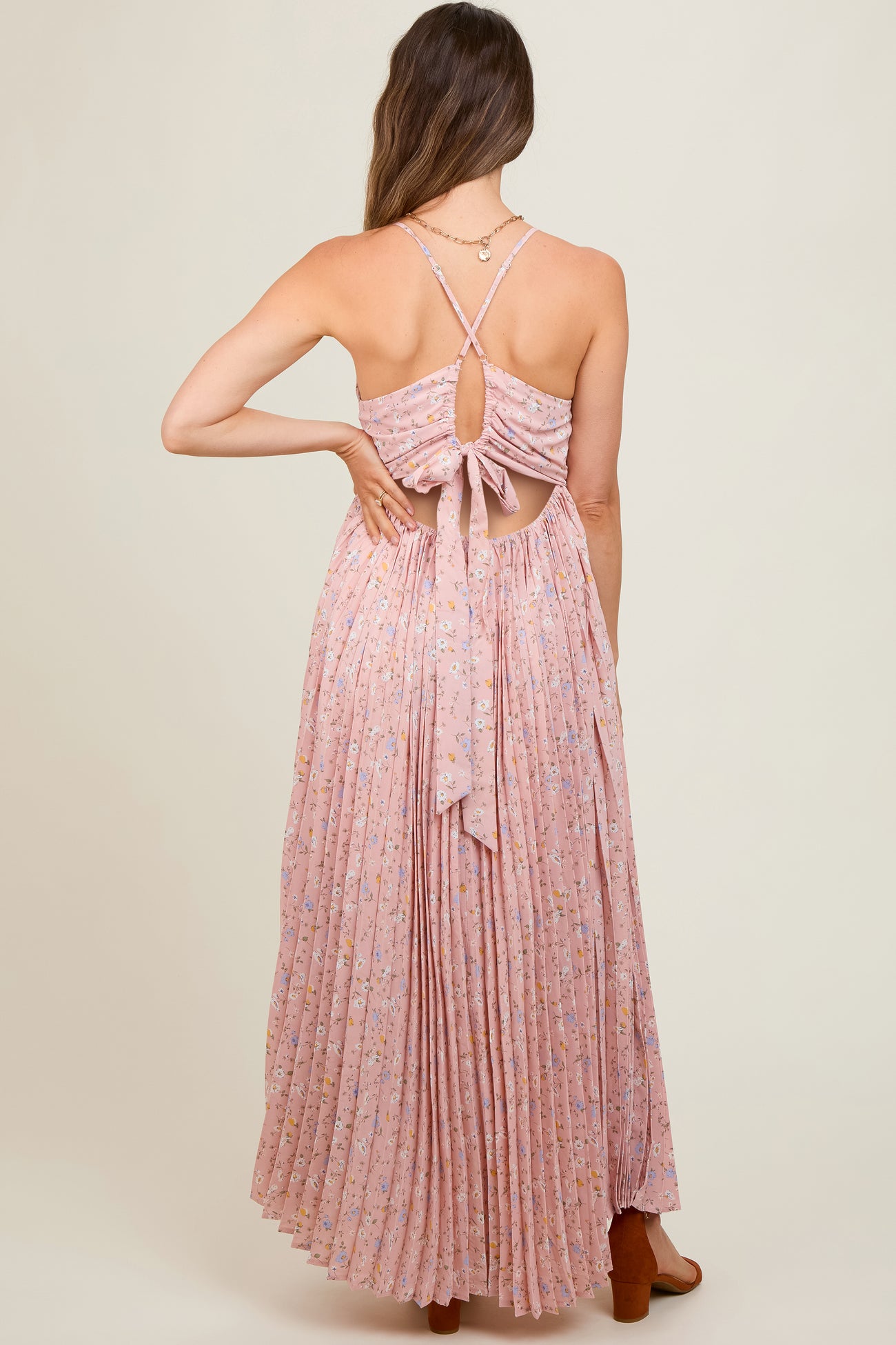 woman wearing a pink floral maternity maxi dress with a tied back and pleated skirt