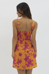 woman wearing a vibrant yellow floral sundress with pink patterns and a smocked back detail