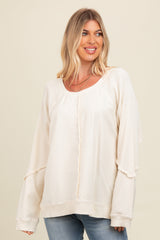 woman wearing a cream oversized sweatshirt with a relaxed fit and ribbed details, styled with light blue jeans