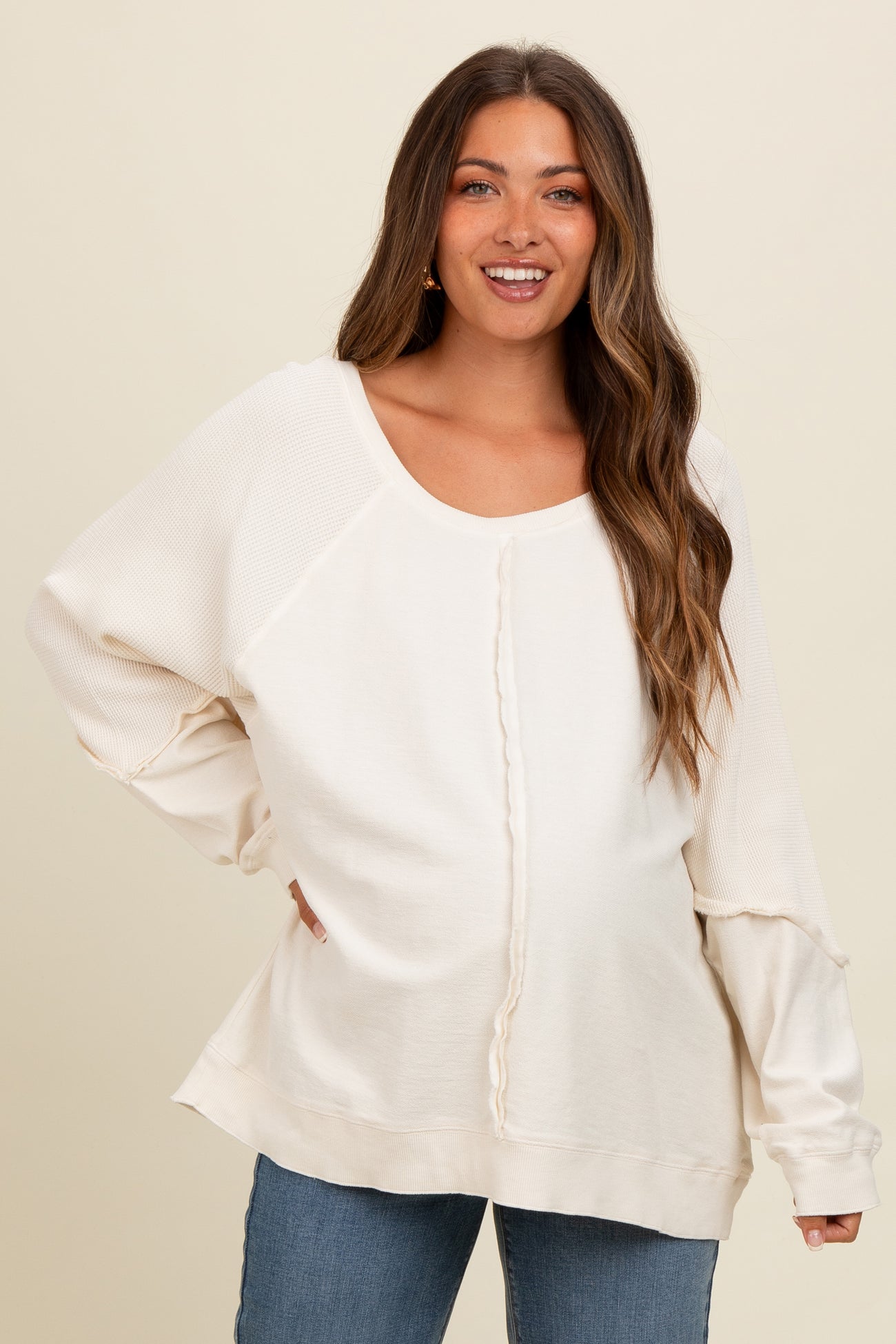 woman wearing a cream maternity sweatshirt with a textured front and relaxed fit, smiling at the camera