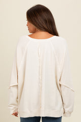 woman wearing a cream maternity sweater with a relaxed fit and back pleat detail