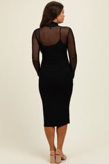 woman wearing a black long sleeve maternity dress with a sheer back and fitted silhouette