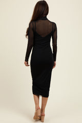 woman wearing a fitted black midi dress with long sheer sleeves and a high neckline, shown from the back