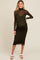 woman wearing a dark olive green maternity dress with a sheer long sleeve overlay and a visible baby bump