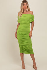 woman wearing a bright green off-the-shoulder midi dress with gathered detailing and a fitted silhouette