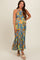 woman wearing a floral patterned maternity maxi dress with a halter neckline and ruffled hem, showcasing her baby bump