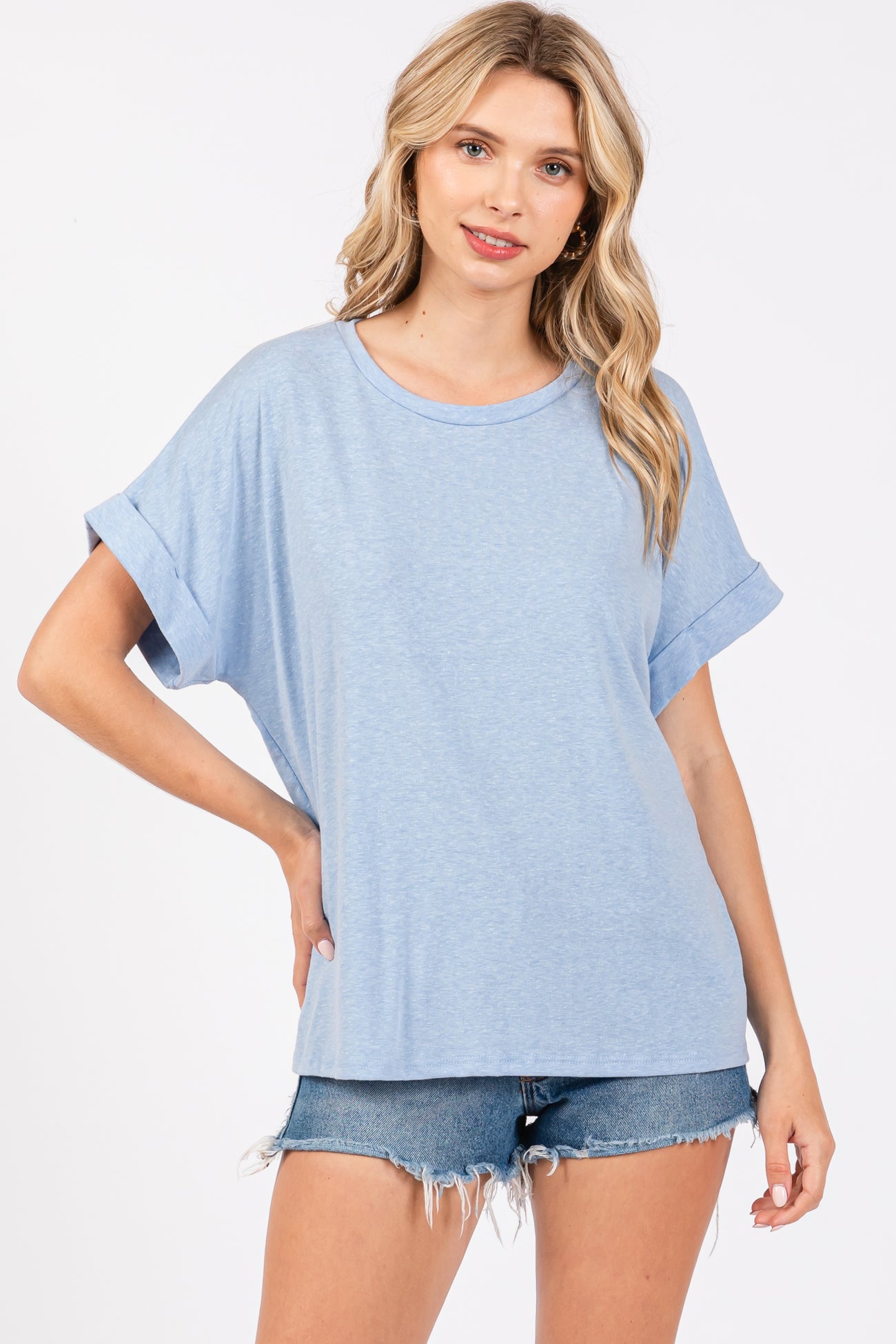 woman wearing a light blue oversized t-shirt with rolled sleeves and styled with denim shorts