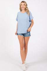 woman wearing a light blue oversized t-shirt with rolled sleeves and distressed denim shorts