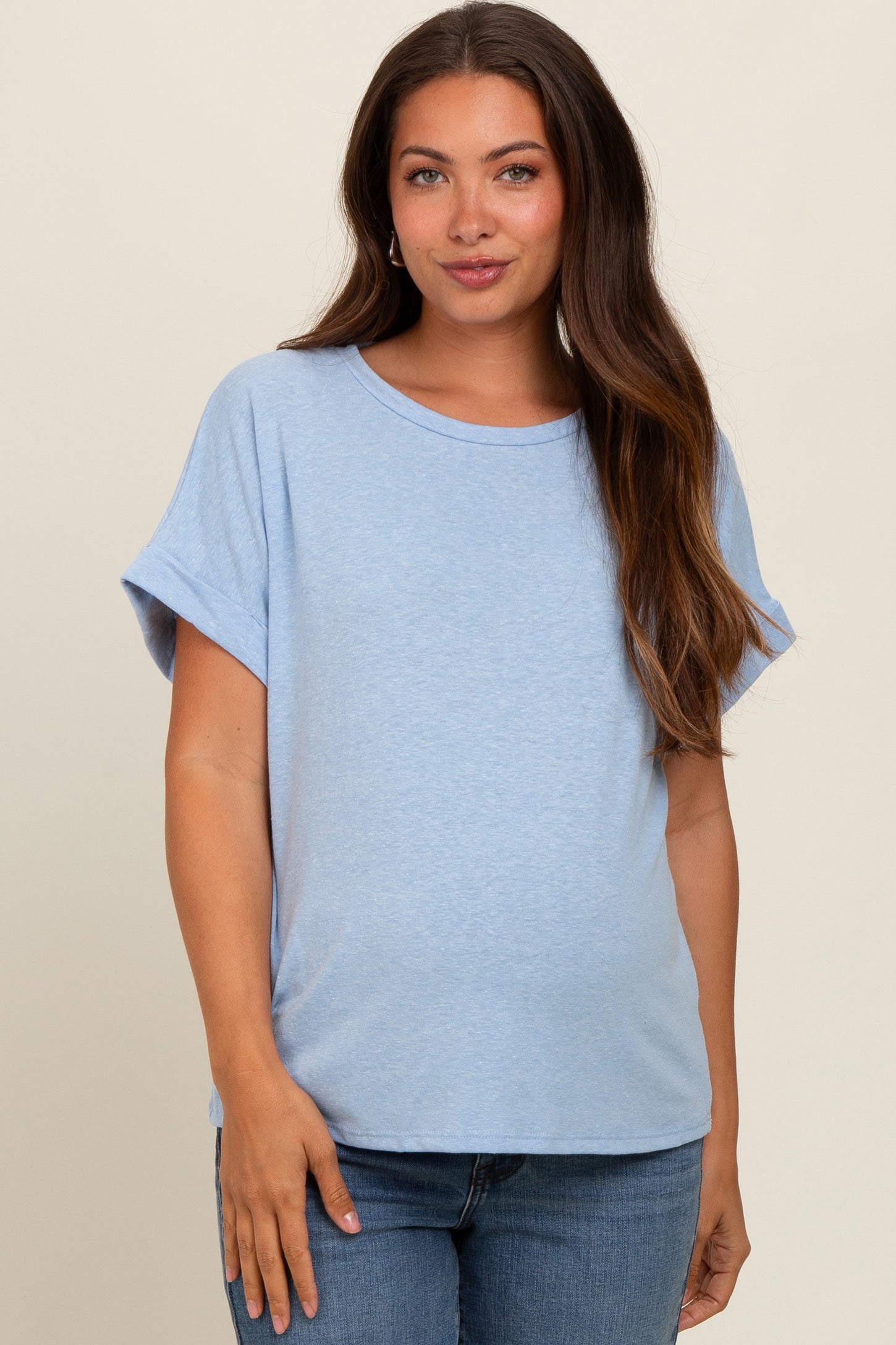 woman wearing a light blue maternity top with rolled sleeves and a visible baby bump