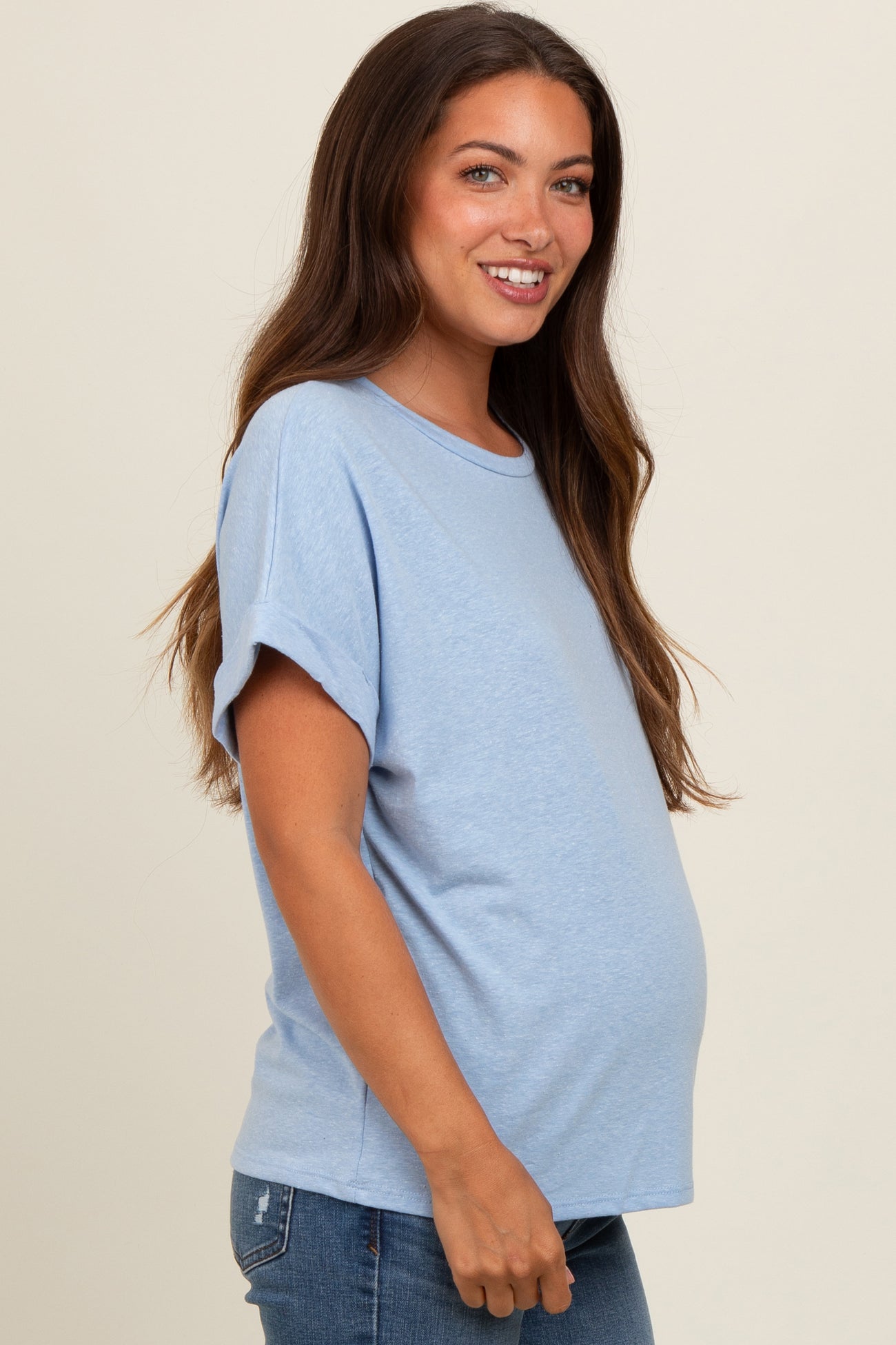 woman wearing a light blue short sleeve maternity top and showing her baby bump