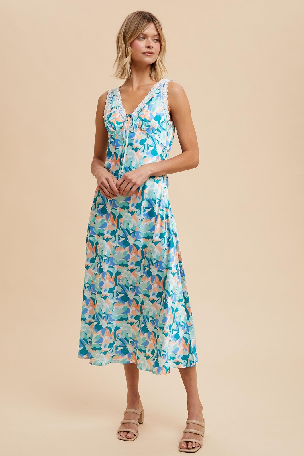 woman wearing a floral print midi dress in shades of blue and pastel colors, featuring a V-neck and sleeveless design