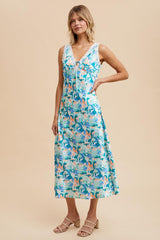 woman wearing a floral patterned sleeveless maxi dress in shades of blue and pastel colors with a v-neckline