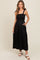 woman wearing a black maxi dress with smocked bodice and tie straps, featuring tiered skirt and pockets