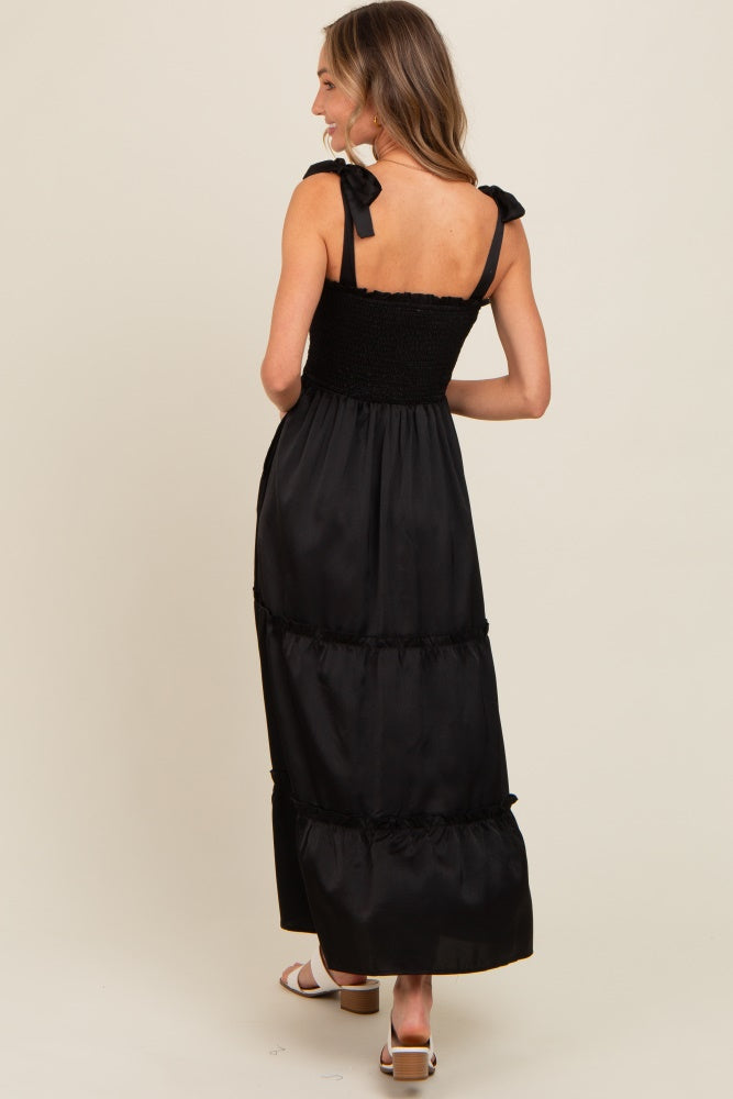 woman wearing a black maxi dress with smocked bodice and bow straps, showing the back view