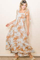 woman wearing a light blue floral maxi dress with tie straps and a flowing skirt