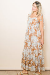 woman wearing a light blue floral maxi dress with tie straps and a tiered skirt