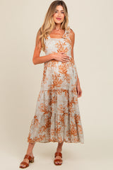 woman wearing a light gray floral print maternity maxi dress with ruffled straps and holding her baby bump