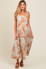 woman wearing a floral print maternity maxi dress with adjustable straps and a flowing skirt, showcasing her baby bump
