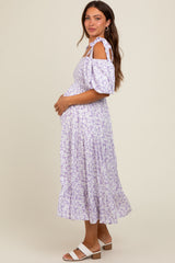woman wearing a lavender floral print maternity dress with cold shoulder sleeves and a visible baby bump