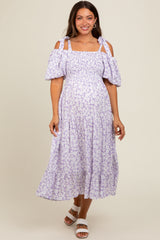 woman wearing a lilac floral cold shoulder maternity dress with puff sleeves and a tiered skirt