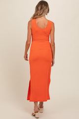 woman wearing a ribbed orange maternity maxi dress with a slit and a fitted silhouette, showing a baby bump