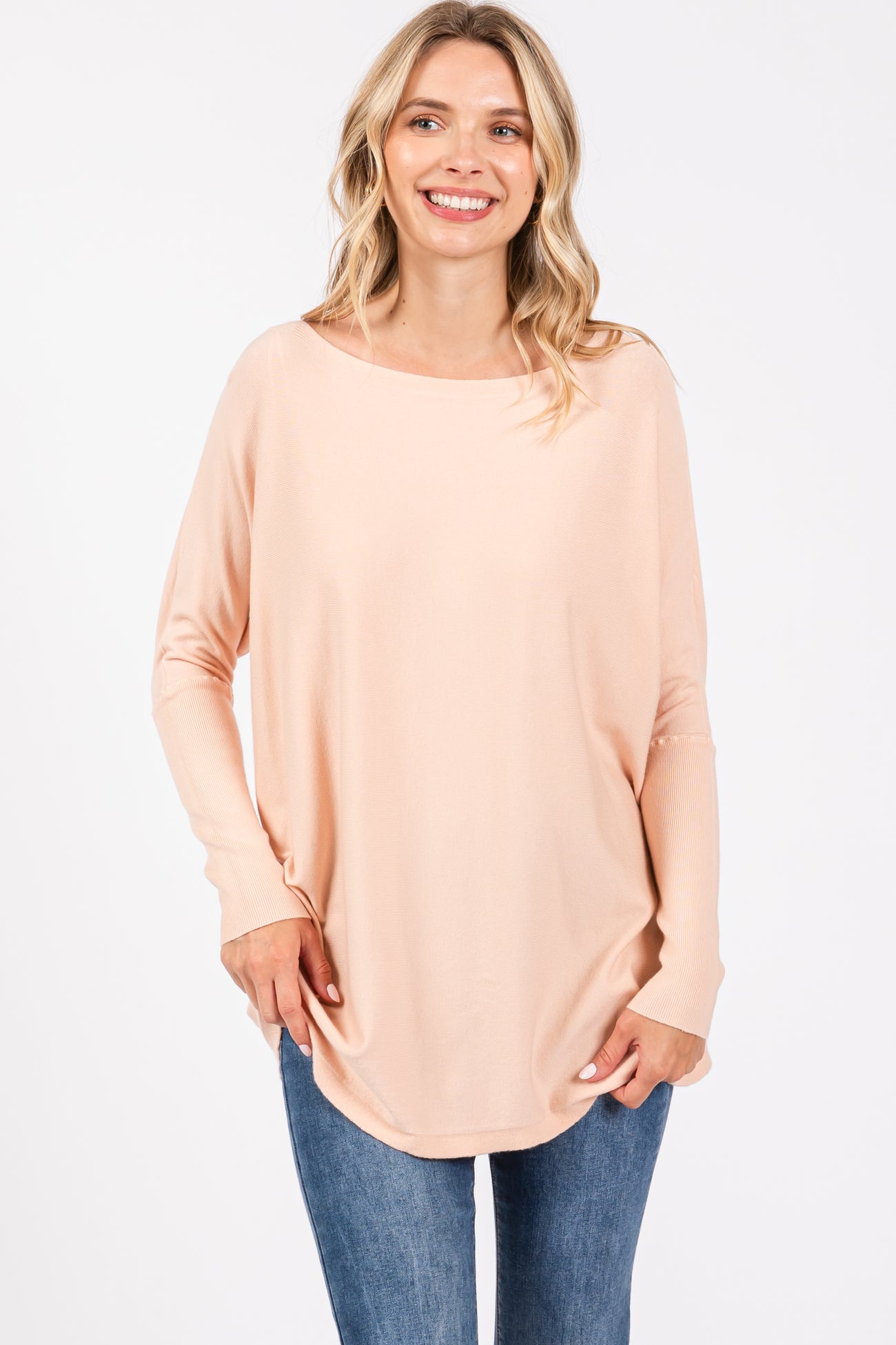 woman wearing a light peach long sleeve oversized top with a round neckline and relaxed fit