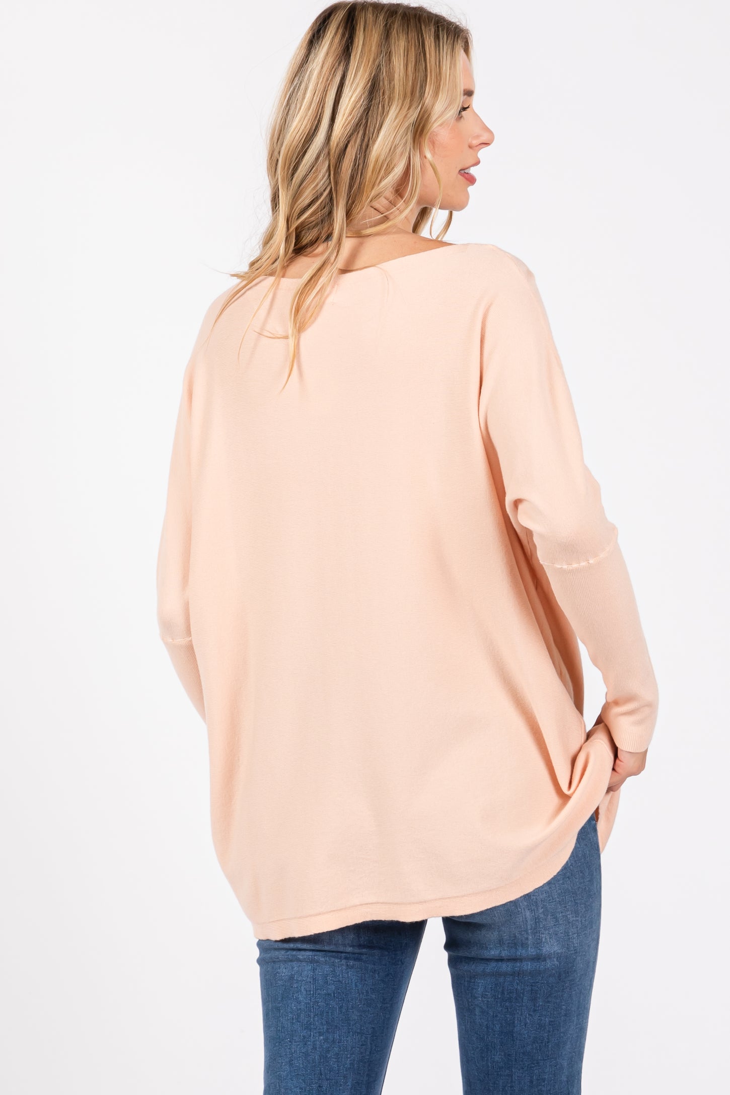 woman wearing a blush pink oversized sweater with a relaxed fit and long sleeves, viewed from the back