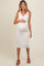 woman wearing a white ribbed maternity dress with buttons, gently cradling her baby bump while smiling