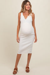 woman wearing a white ribbed maternity dress with a v-neck and button details, highlighting her baby bump