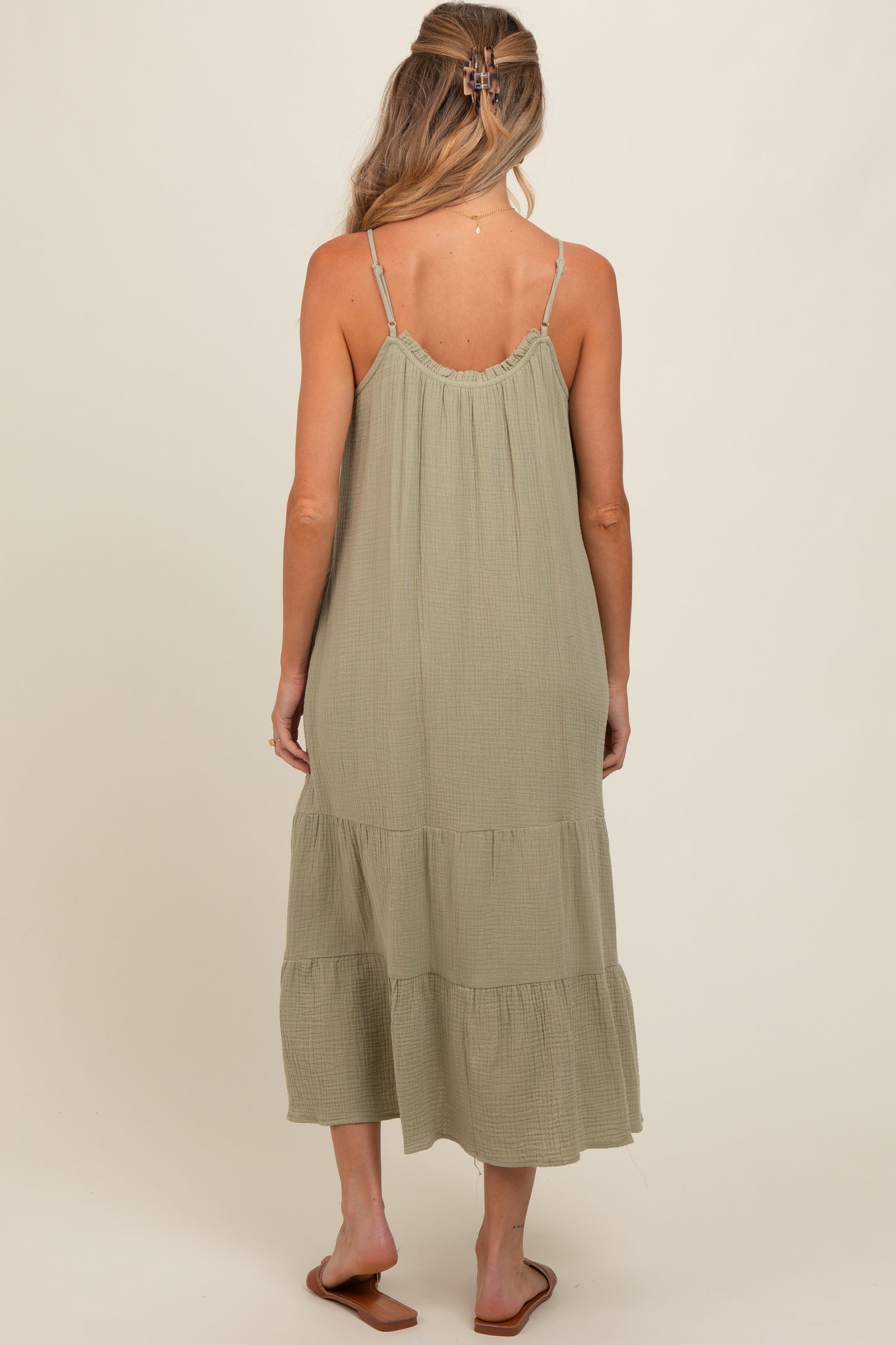 woman wearing a light green tiered maternity dress with thin straps, showing the back view