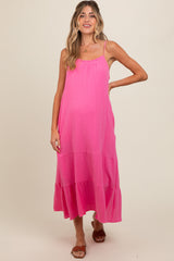 woman wearing a pink maternity maxi dress with adjustable straps and tiered skirt, highlighting her baby bump
