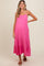 woman wearing a pink maternity maxi dress with adjustable straps and tiered skirt, highlighting her baby bump