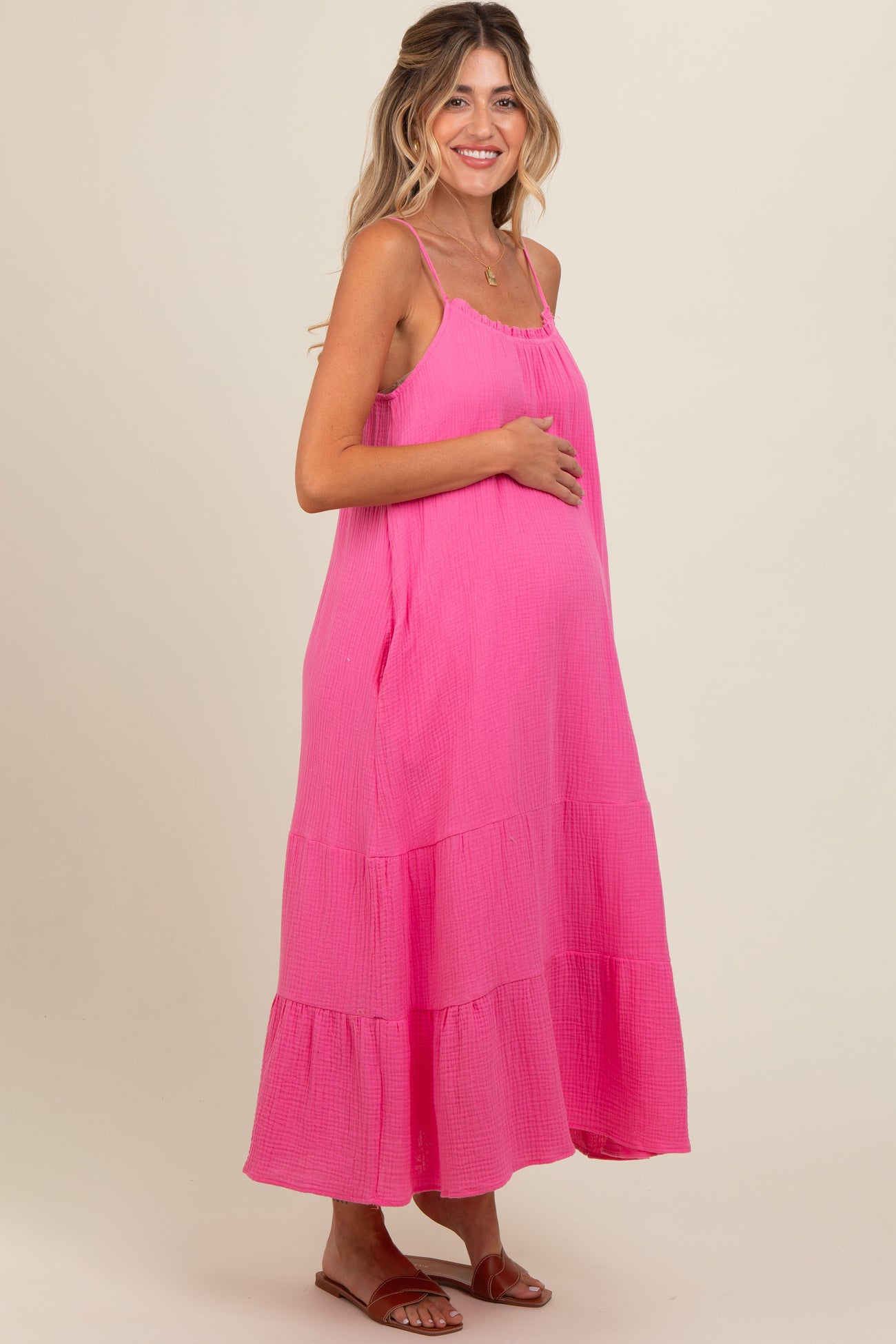 woman wearing a hot pink maternity dress with tiered layers and a visible baby bump