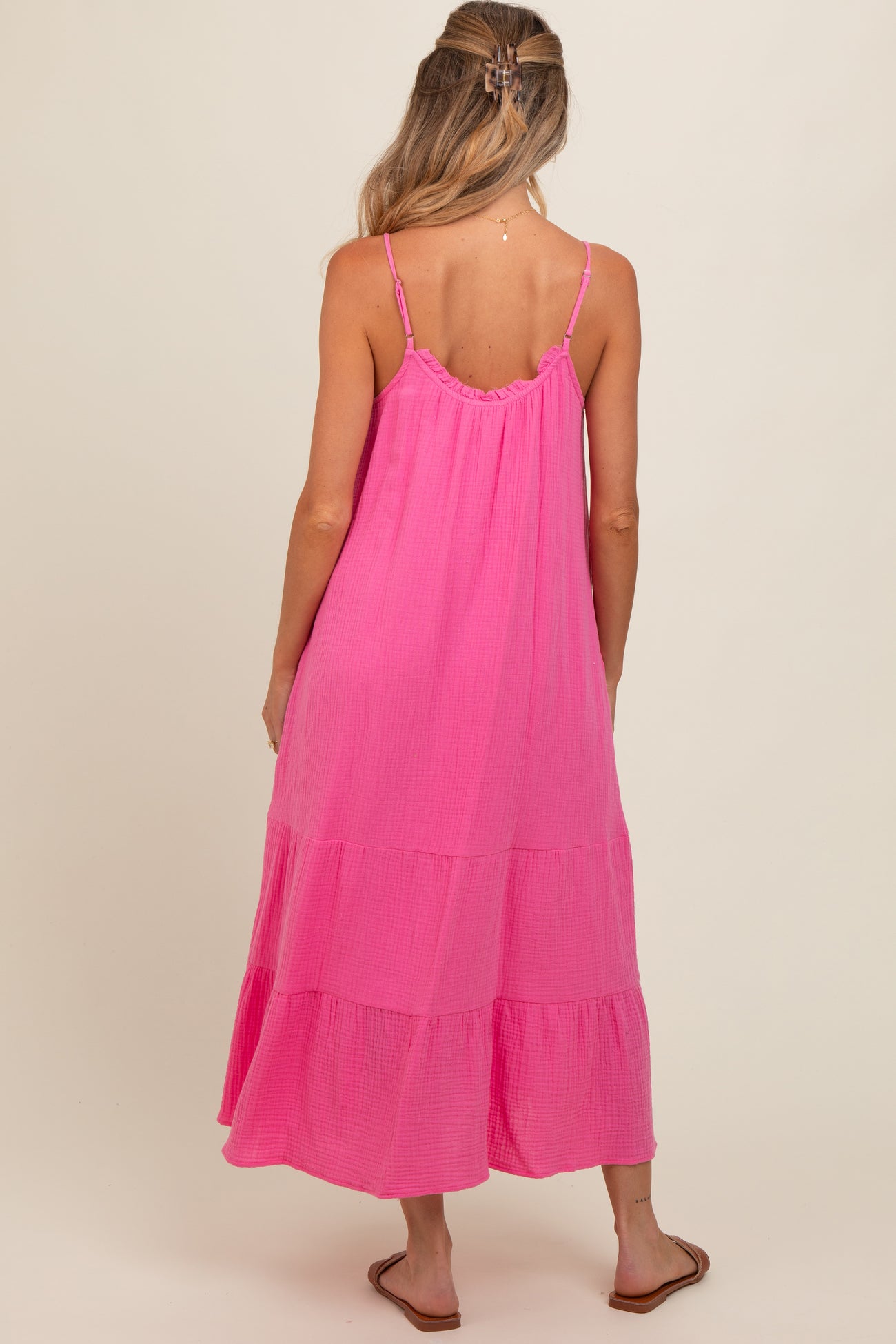 woman wearing a pink maternity maxi dress with tiered layers and thin straps, showing her baby bump from the back