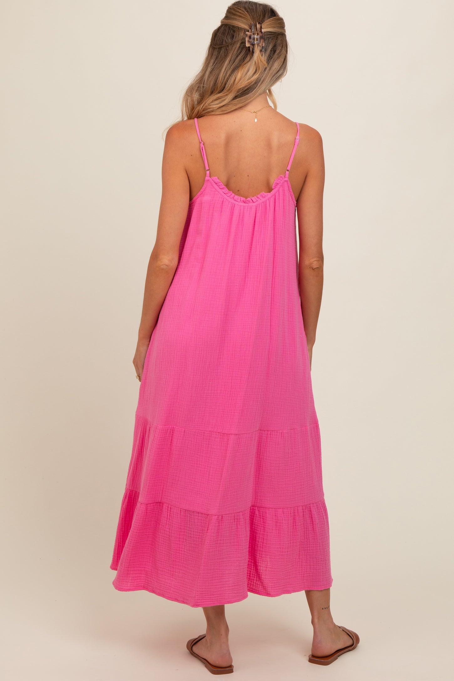 woman wearing a pink maternity maxi dress with tiered layers and thin straps, showing her baby bump from the back