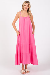 woman wearing a pink tiered maxi dress with adjustable spaghetti straps and side pockets