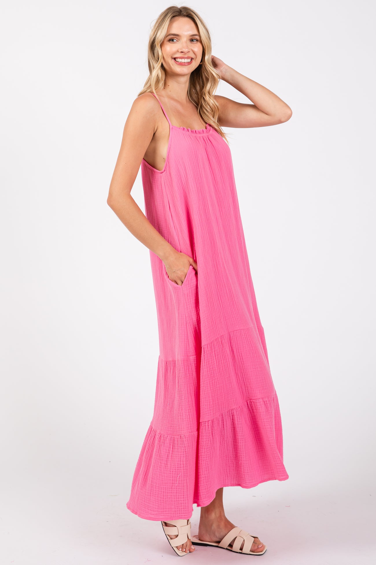 woman wearing a bright pink sleeveless maxi dress with pockets and a tiered design
