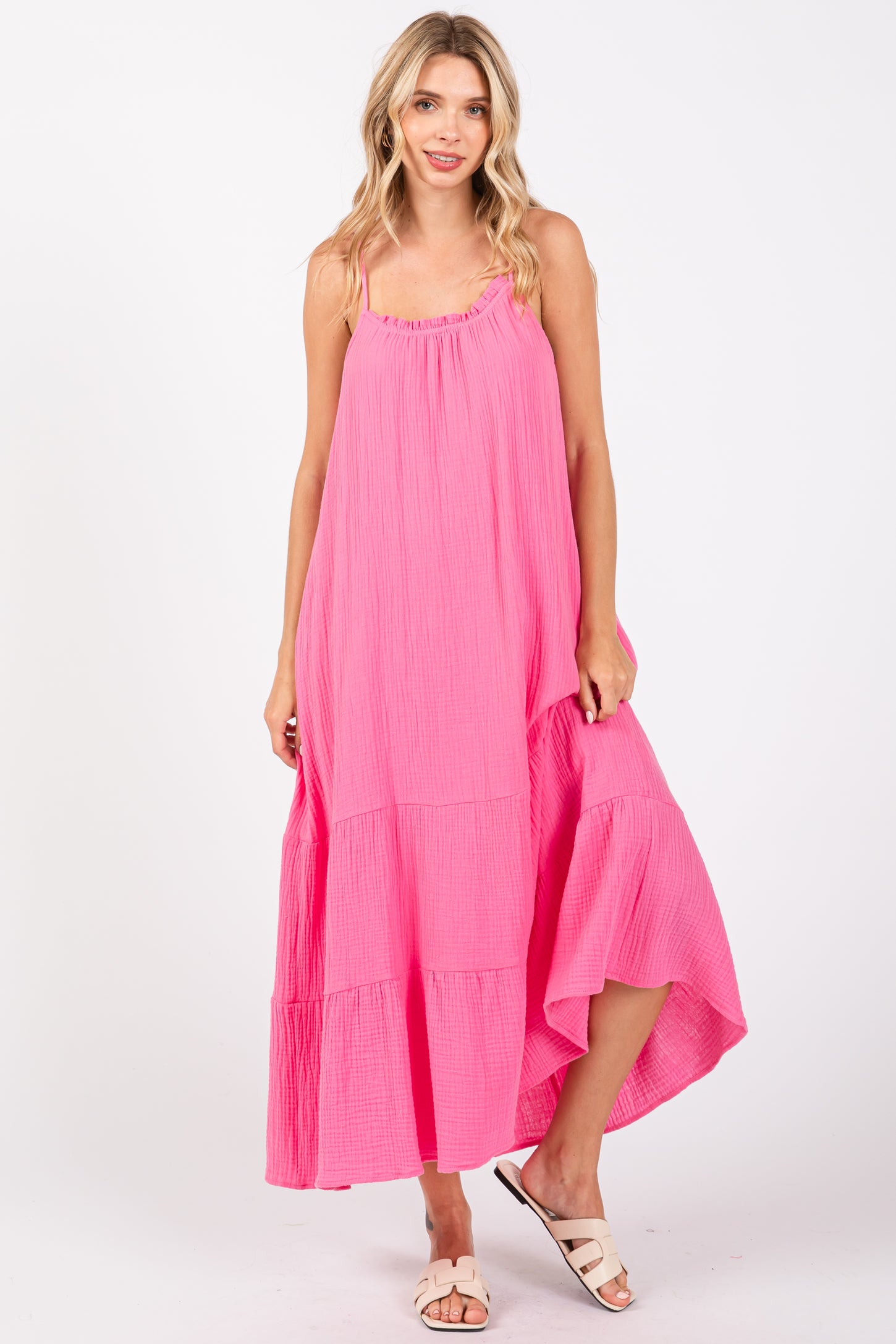 woman wearing a bright pink maxi dress with tiered detailing and spaghetti straps