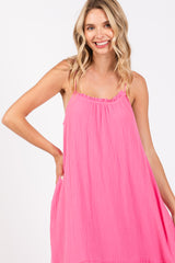 woman wearing a pink sleeveless maxi dress with a ruffled neckline and a relaxed fit.