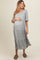 woman wearing a grey maternity dress with short puff sleeves and tiered skirt, gently holding her baby bump