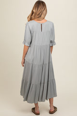 woman wearing a light grey tiered maternity dress, showing back view with short puff sleeves and keyhole detail