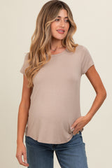 woman wearing a light taupe short sleeve maternity top and showcasing her baby bump