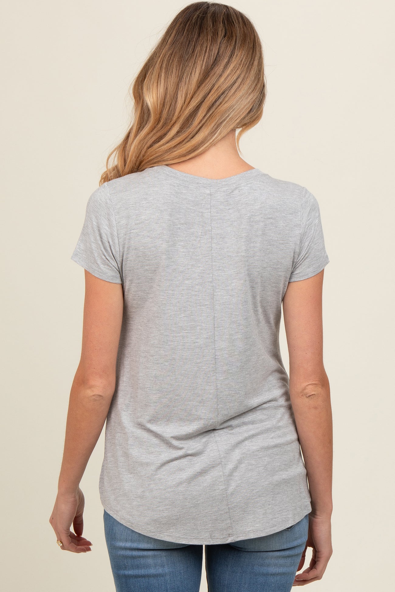 woman wearing a gray short sleeve maternity top, shown from the back, paired with blue jeans