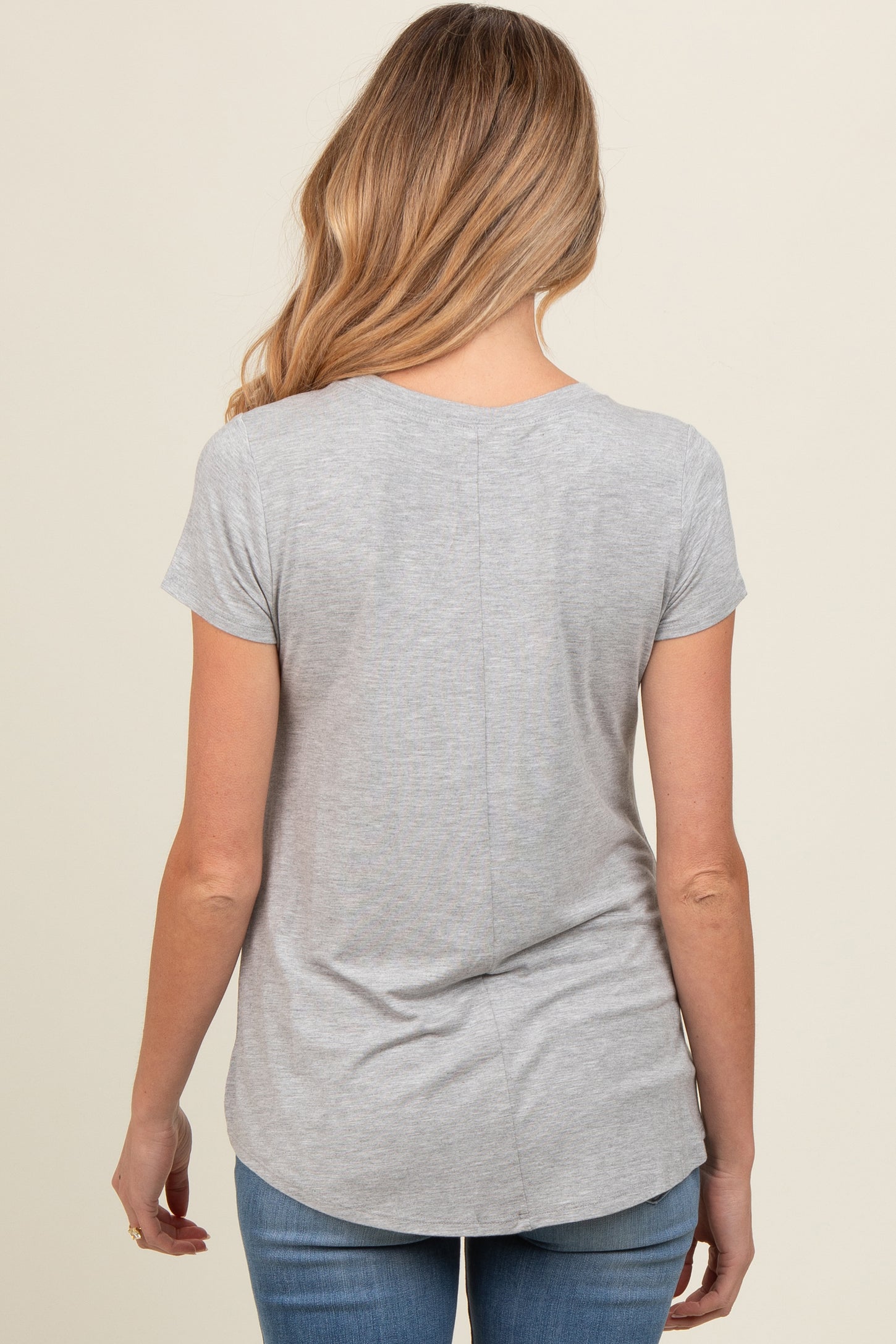 woman wearing a gray short sleeve maternity top, shown from the back, paired with blue jeans