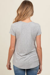 woman wearing a gray short sleeve maternity top, shown from the back, paired with blue jeans
