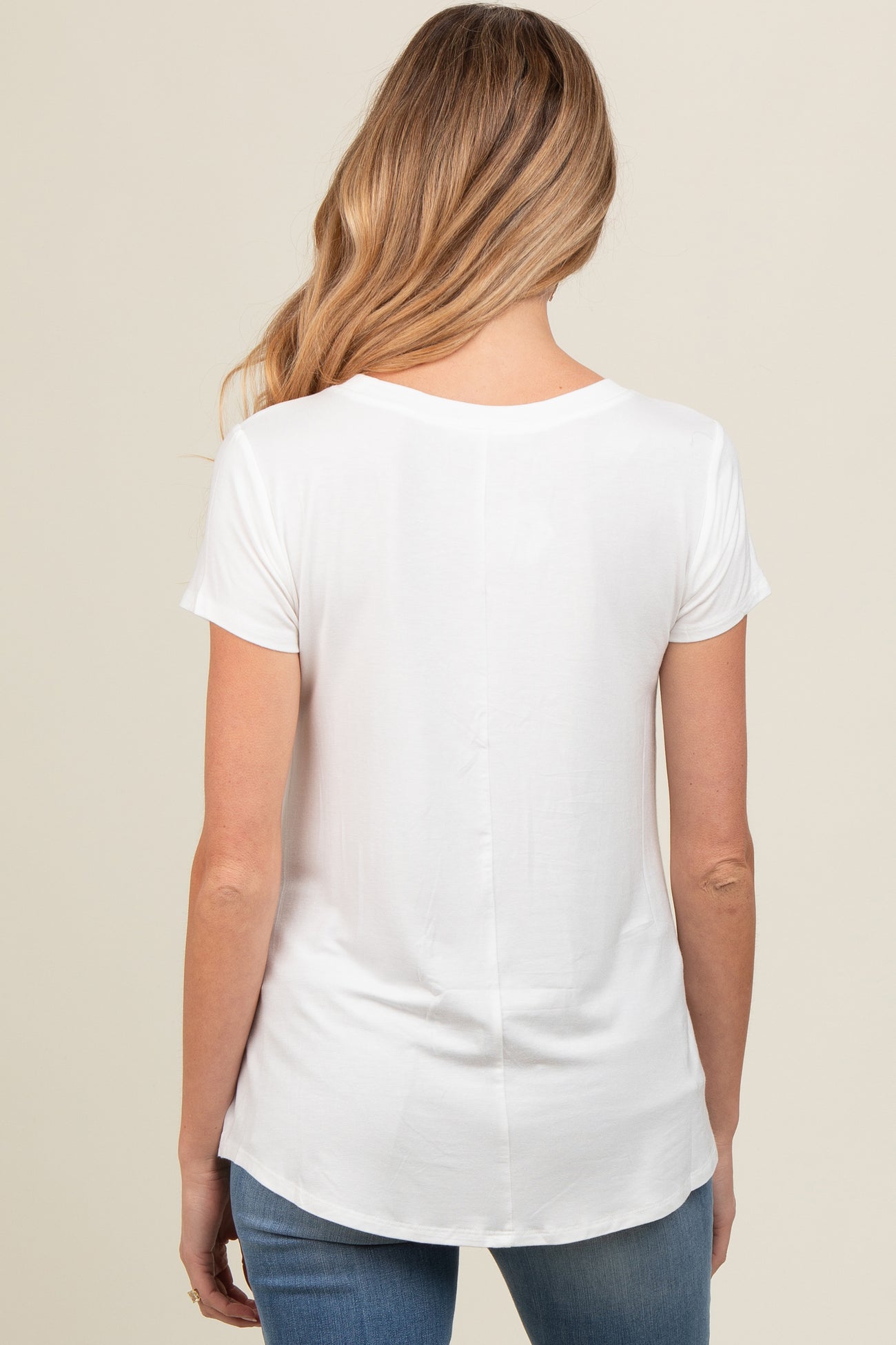 woman wearing a white short sleeve maternity top, viewed from the back, paired with blue jeans