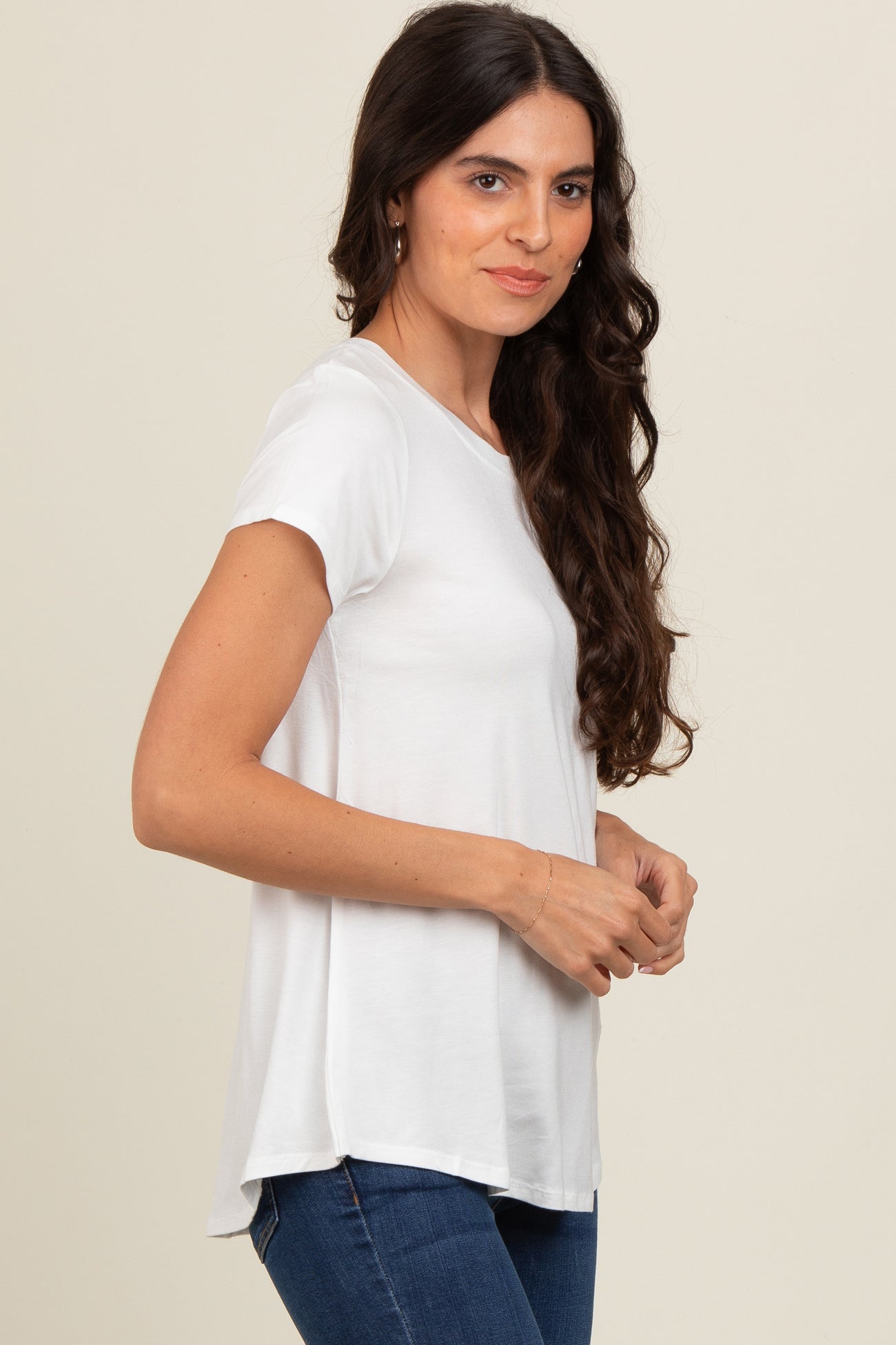 woman wearing a white short sleeve top with a relaxed fit and side slits, paired with blue jeans