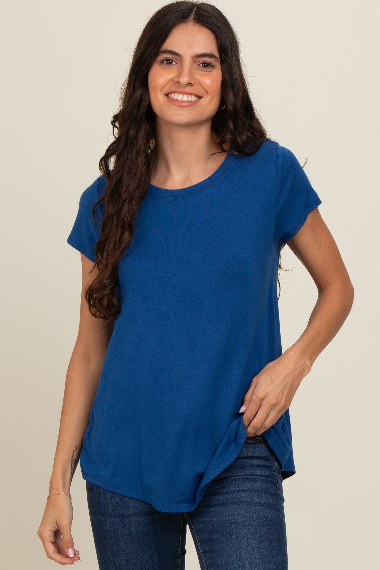 woman wearing a blue short sleeve t-shirt with a curved hem and relaxed fit, smiling at the camera