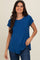 woman wearing a blue short sleeve t-shirt with a curved hem and relaxed fit, smiling at the camera