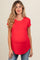 woman wearing a red short sleeve maternity top that highlights her baby bump with a curved hem, paired with jeans